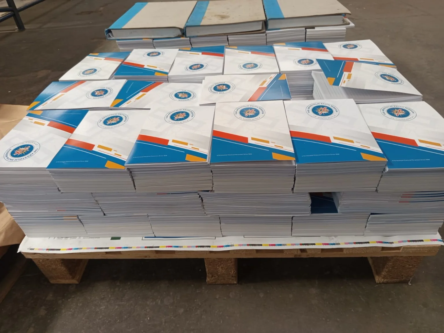 Finished branded notepads stacked on a pallet during a commercial print run