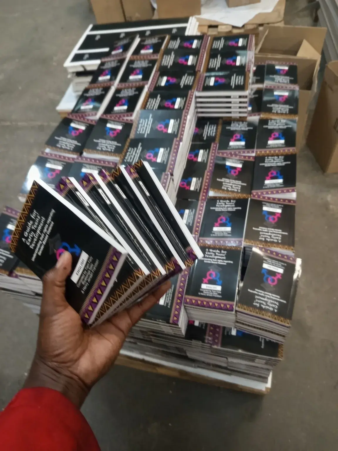 Finished bound books held in front of a bulk production pallet