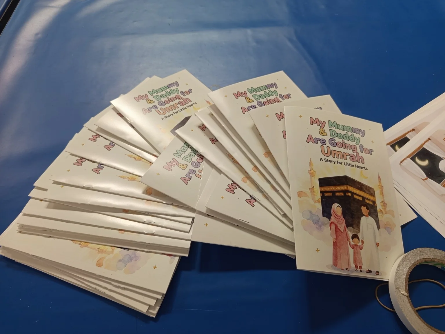 Saddle-stitched Umrah booklets stacked after folding and stapling during finishing