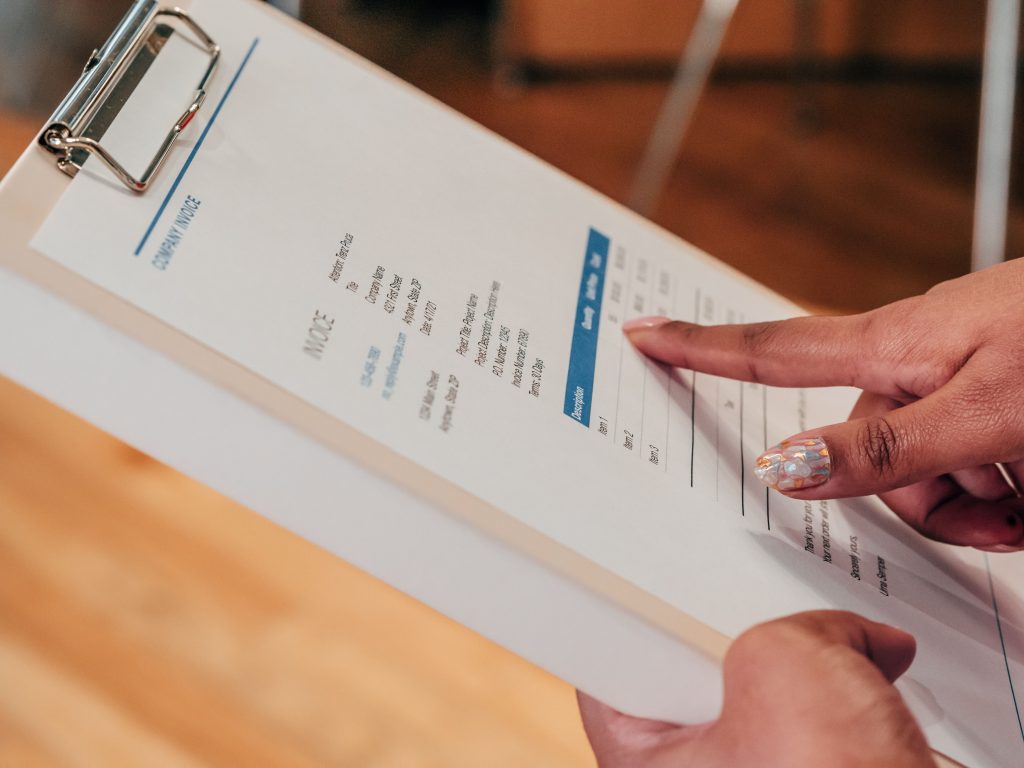INVOICE BOOK PRINTING JOHANNESBURG Close-up image of a person pointing to a document on a clipboard, indoors.